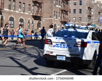 Brooklyn, NY, US - Nov. 4, 2018: A Police Car Moves Alongside Runners At The New York City Marathon, Behind Blue Tape Marking The Course At Brooklyn's Fourth Avenue.