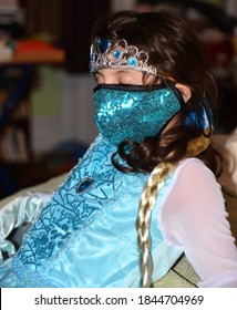 Brooklyn, NY, US - Oct. 31, 2020: A young girl closes her eyes in her bedroom, while wearing a teal sequined face mask as part of her Halloween costume as Queen Elsa from Disney's "Frozen."