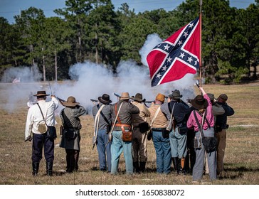 Brooksville, FL - January 18, 2020: Confederate Battle Flag Flies Over A Group Of Civil War Reenactors As They Fire On The Enemy.