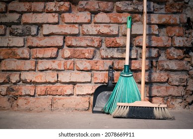 Broom and dust pan on the dirty dusty floor of a construction site room background.