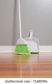 A Broom And Dust Pan On New Hardwood Flooring