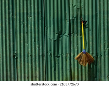 Broom Hangs On An Old Green Zinc Fence