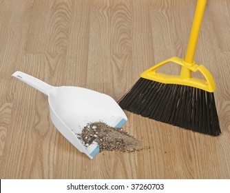 Broom Sweeping Up Dirt Into Dust Pan On Hardwood Floor