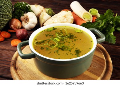 Broth with carrots, onions various fresh vegetables in a pot - colorful fresh clear spring soup. Rural kitchen scenery vegetarian bouillon - Powered by Shutterstock