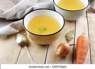 Broth With Ingredients.Clear Broth Is Made By Simmering  Meat Or Bones And Vegetables. Prepared With Carrot, Onion, Root Parsley, Celery And Served In To The Bowls On The Table.Food Concept.