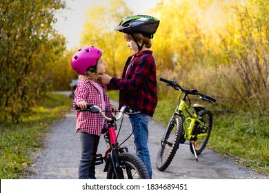 the brother helps the younger sister to put on and fasten a protective helmet for a Bicycle - Powered by Shutterstock