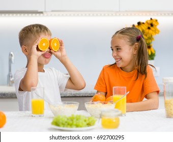 Brother laughs at his sister with orange before his eyes like in glasses - Powered by Shutterstock