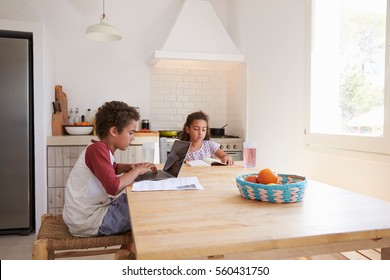 Brother And Sister Doing Homework At Kitchen Table