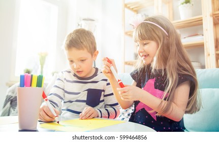 Brother and sister drawing with colorful pencils together at home - Shutterstock ID 599464856