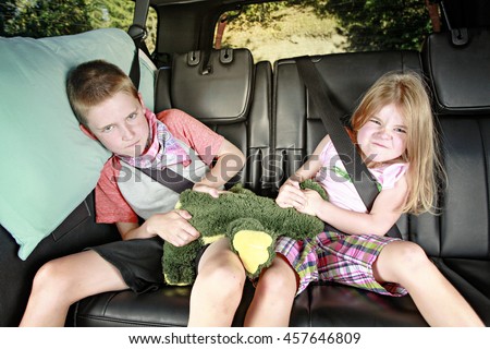 Brother and sister fighting in the back of a car