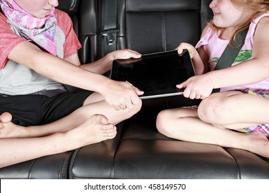 A Brother And Sister Fighting Over A Tablet In The Back Of A Car A Brother And Sister Fighting Over A Tablet In The Back Of A Car