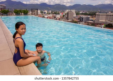 brother and sister having fun at the poolside, looking toward camera at a rooftop swimming pool during summer holiday - Powered by Shutterstock