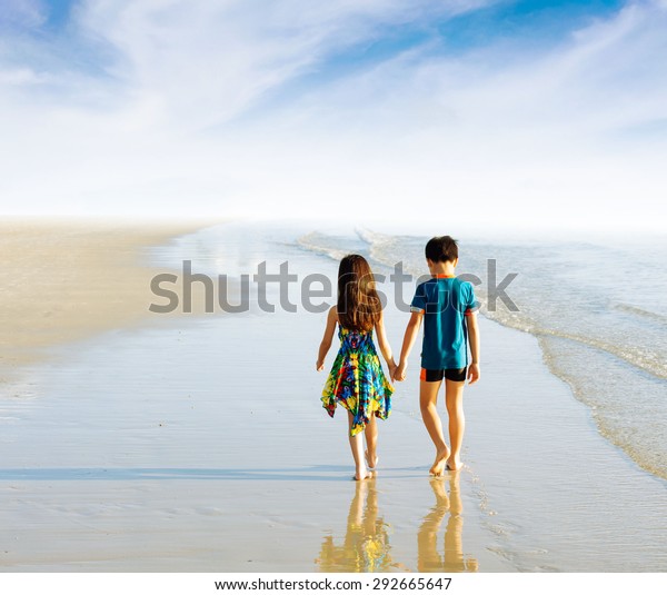 Brother Sister Holding Hand Walk On The Beach In Tropical Seaside Under