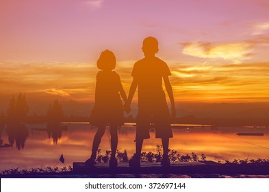 Brother And Sister Holding Hands Together With Sun Set.