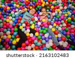 Brother with sister playing in colorful ball pit. Day care indoor playground. Balls pool for children. Kindergarten or preschool play room.