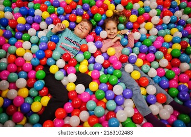 Brother with sister playing in colorful ball pit. Day care indoor playground. Balls pool for children. Kindergarten or preschool play room.