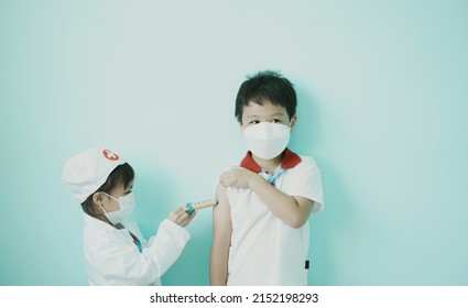 Brother and sister are playing doctor and hospital using toy wooden syringe  and medical uniform at home. Soft focus.