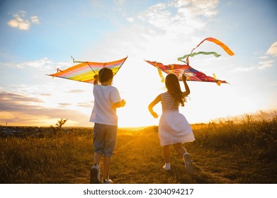 Brother and sister playing with kite and plane at the field on the sunset - Powered by Shutterstock