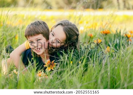 Brother and sister posing together in field of wild gazania flowers