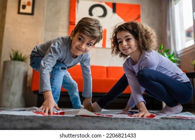 Brother And Sister Siblings Small Caucasian Boy And Girl Child Play Twister Game On The Floor At Home Alone Real People Family Growing Up Leisure Concept Copy Space