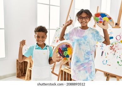 Brother and sister smiling confident holding paintbrush and palette at art studio - Powered by Shutterstock
