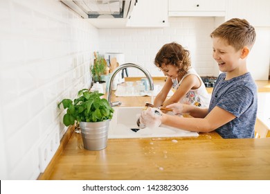 Brother and sister washing dishes together in the kitchen at home. Modern white kitchen scandinavian style, zero waste eco friendly home