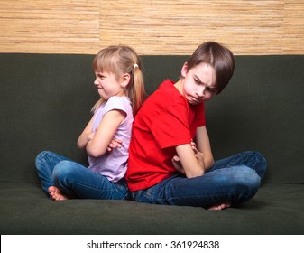 Brother And Sister Wearing Casual Clothes Sitting On A Green Sofa At Home Arms Crossed Back Brother And Sister Wearing Casual Clothes Sitting On A Green Sofa At Home Arms Crossed Back