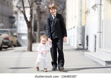Brother and sister wearing formal clothes walking on a sunny street