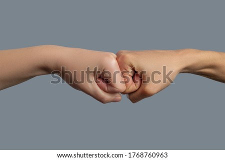 Brotherhood of mankind. Close-up of light-skinned and dark-skinned fists bumping together
