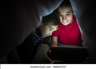 Brothers kids with tablet computer under blanket at night in a dark room - Powered by Shutterstock