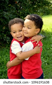 Brothers love. Twin african american brother hugging strong his lovely brother. Very cute boys. Curly hair. Walking with twins outside. Not identical twins. Children outside. Summer holidays. 