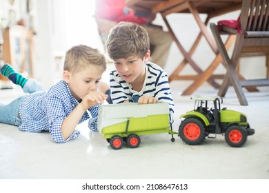 Brothers playing with toy tractor on floor - Powered by Shutterstock