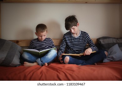 The Brothers Read Together On Two Bunk Beds In The Nursery, The Concept Of Kinship And Childhood, A Real Interior, A Dark Style