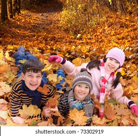 	Brothers And Sister Playing Outside In Autumn Leaves.