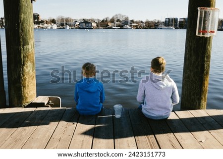 Brothers sit on edge of dock overlooking harbor water