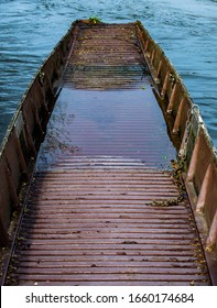 Brown Abandoned Row Boat, Vintage Wooden Boat Sinking With Leaves And Water Inside, Damaged And Left To Rot Rowing Boat.