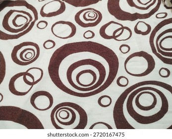 Brown Abstract Circle Pattern on White Fabric Texture Background, A top-down view of a textile featuring a repetitive pattern of chocolate brown concentric circles and rings on a white cloth surface. This clean, modern abstract design is ideal for interior decor, fashion industry backgrounds, or fabric material samples. - Powered by Shutterstock - Get 15% off with code: PIKWIZARD15