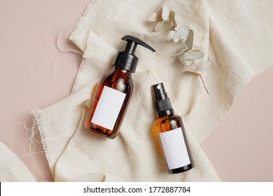 Brown Amber Glass Bottles Mockup On Beige Fabric. Flat Lay, Top View. Cosmetic Packaging Design For Hair Lotion, Organic Shampoo, Body Spray.