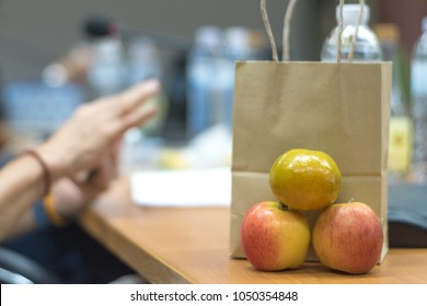 Brown Bag Lunch Meeting Concept. Paper Bag Contains Food, Snack, Fruit And Water  For Officer In Office In Conference With Hand On Colleague Working On Table. 