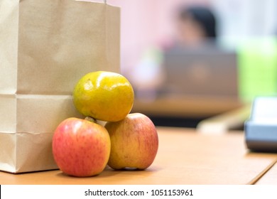 Brown Bag Lunch Meeting Concept. Paper Bag Contains Food, Snack, Fruit And Water  For Officer In Office In Conference With Hand On Colleague Working On Table. 