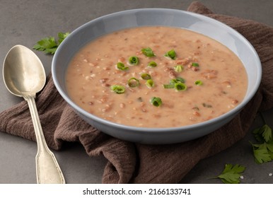 Brown Bean Soup In A Bowl With Seasoning Over Stone Background.