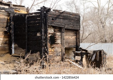 Brown And Black Burnt House Of Wooden Planks With Embossed Texture Without Door And Broken Wall. 
Damage To The Building From Fire Without The Possibility Of Its Restoration. Property Insurance.