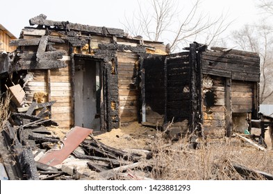 Brown And Black Burnt House Of Wooden Planks With Embossed Texture Without Door And Broken Wall. 
Damage To The Building From Fire Without The Possibility Of Its Restoration.  Property Insurance.