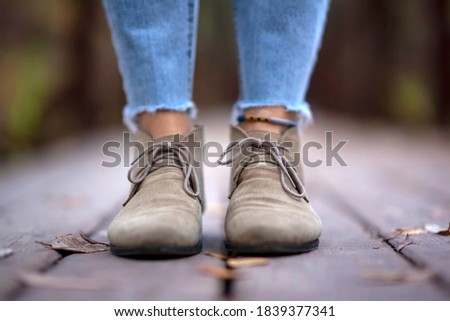 Brown boots with laces of a traveler on the feet of a woman close-up on a wooden bridge on an autumn day