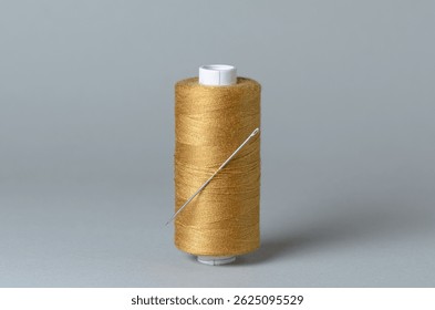 Brown bronze thread spool with needle close-up flat lay top view background with copy space for text