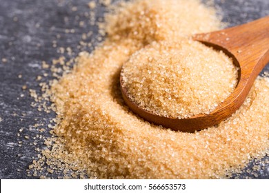 brown cane sugar in a wooden spoon.