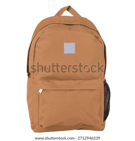 A brown canvas backpack is shown from the front against a white background. It features a main compartment, a zippered front pocket, and a mesh side pocket. A small grey square patch is visible on the upper front.