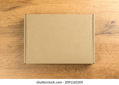 Brown Cardboard Box On Wooden Table Background. Mockup Photo, Concept Of Delivery And Shipping Your Products And Goods Etc.