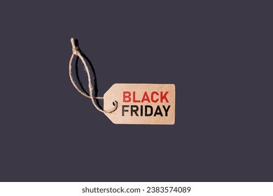 Brown cardboard tag with string, on a black background with red and black letters that say: 'Black Friday'. Concept of black Friday, offers, promotion, cheap prices, sales and consumerism.