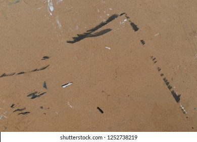 Brown cardboard texture of a drawing board for artists that has black and white paint and scratches and other misc markings.